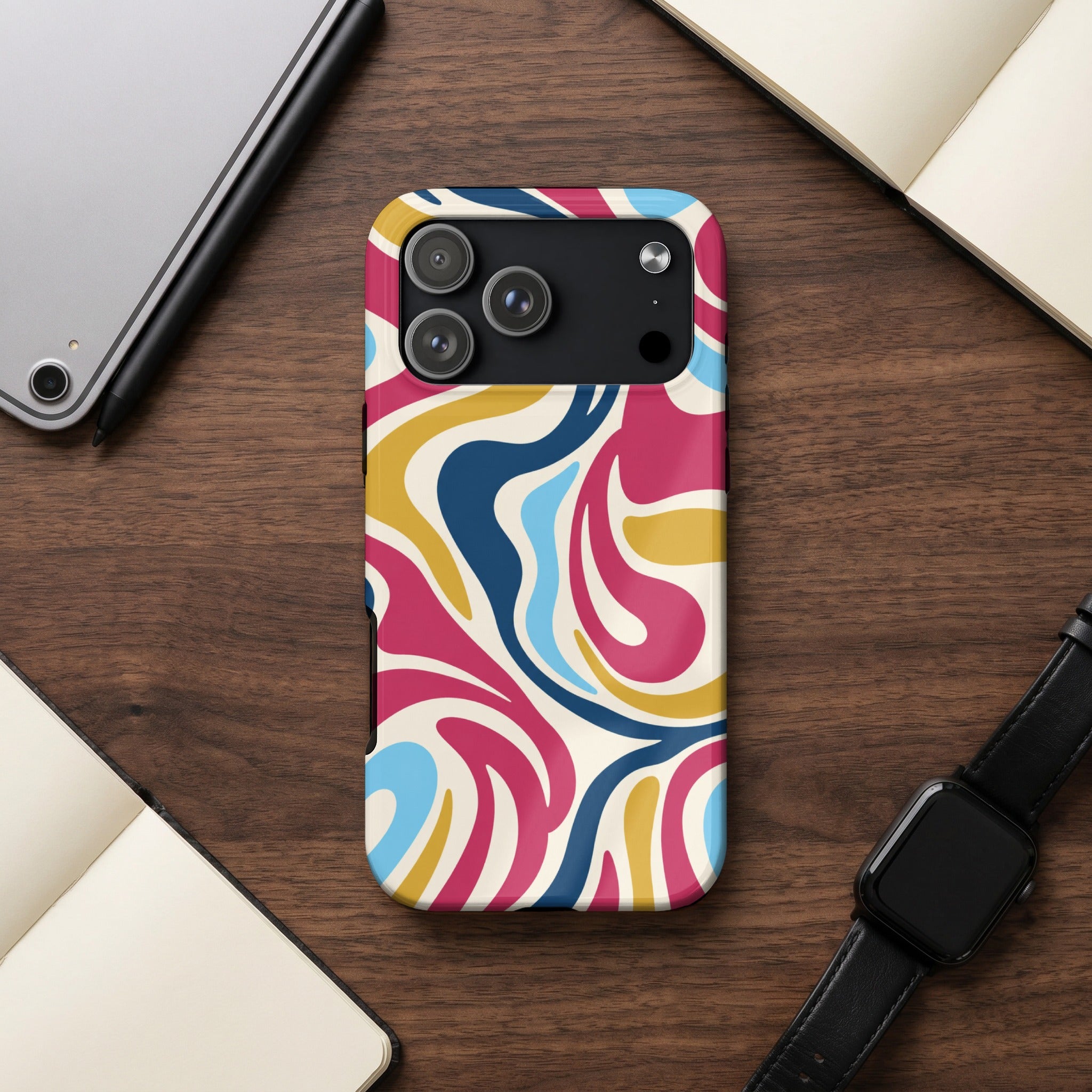 iPhone case with colorful abstract swirl pattern on wooden desk next to tablet and watch.